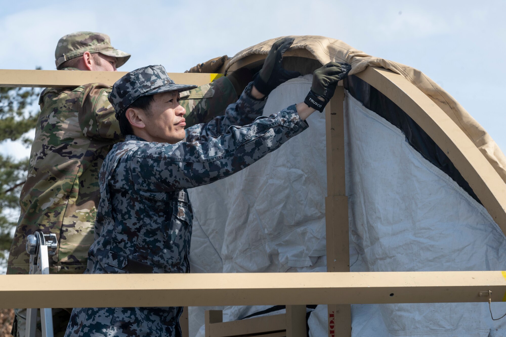 A Japan Air Self-Defense Force (JASDF) Airman and a U.S. Air Force Airman assemble a Small Shelter System during the capstone event of a Multi-Capable Airman course at Misawa Air Base, Japan, March 8, 2024.