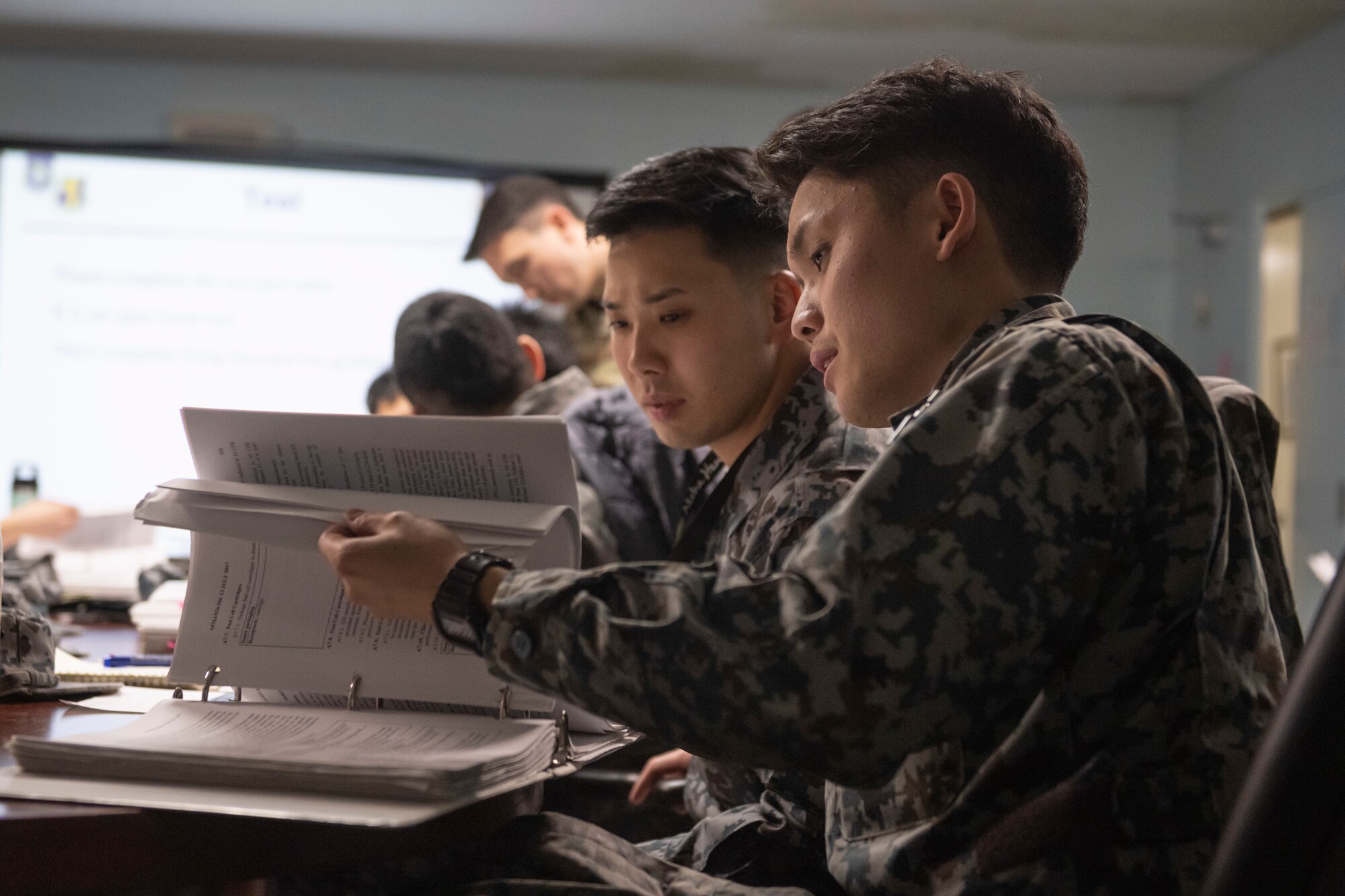 Japan Air Self-Defense Force (JASDF) Airmen flip through the pages of a test during a Multi-Capable Airman (MCA) course at Misawa Air Base, Japan, March 5, 2024.