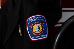 A man, Kenneth Doan, smiles and poses for a picture. In the background, a red firetruck. "EMS" is visible over his shoulder and an open door reads "UNITED STATES AIR FORCE".