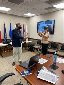 Two people stand in a conference room wearing smart goggles.