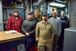 The crew of Naval Undersea Warfare Center Division, Keyport’s Yard Torpedo Test Range Craft “Battle Point” (YTT 10) pictured in the engine room. The marine mechanics maintaining YTT 10 have achieved “miracles” in their ongoing efforts to rejuvenate the aging vessel, according to Brian Adams, head of the command’s Undersea Test Ranges Division. (U.S. Navy photo by Anna Taylor/Released)