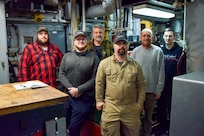 The crew of Naval Undersea Warfare Center Division, Keyport’s Yard Torpedo Test Range Craft “Battle Point” (YTT 10) pictured in the engine room. The marine mechanics maintaining YTT 10 have achieved “miracles” in their ongoing efforts to rejuvenate the aging vessel, according to Brian Adams, head of the command’s Undersea Test Ranges Division. (U.S. Navy photo by Anna Taylor/Released)