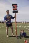 U.S. Marine Corps Gunnery Sgt. Shane Phanthumchinda, an administrative specialist with Headquarters and Service Battalion and Pfc. Bruno, the mascot of Marine Corps Recruit Depot San Diego and the Western Recruiting Region, pose for a picture during the Commanding General's Cup flag football game at Marine Corps Recruit Depot, San Diego, March 6, 2024. The mascot's job is to boost morale, participate in outreach work and attend events and ceremonies. (U.S. Marine Corps photo by Lance Cpl. Alexandra Earl)