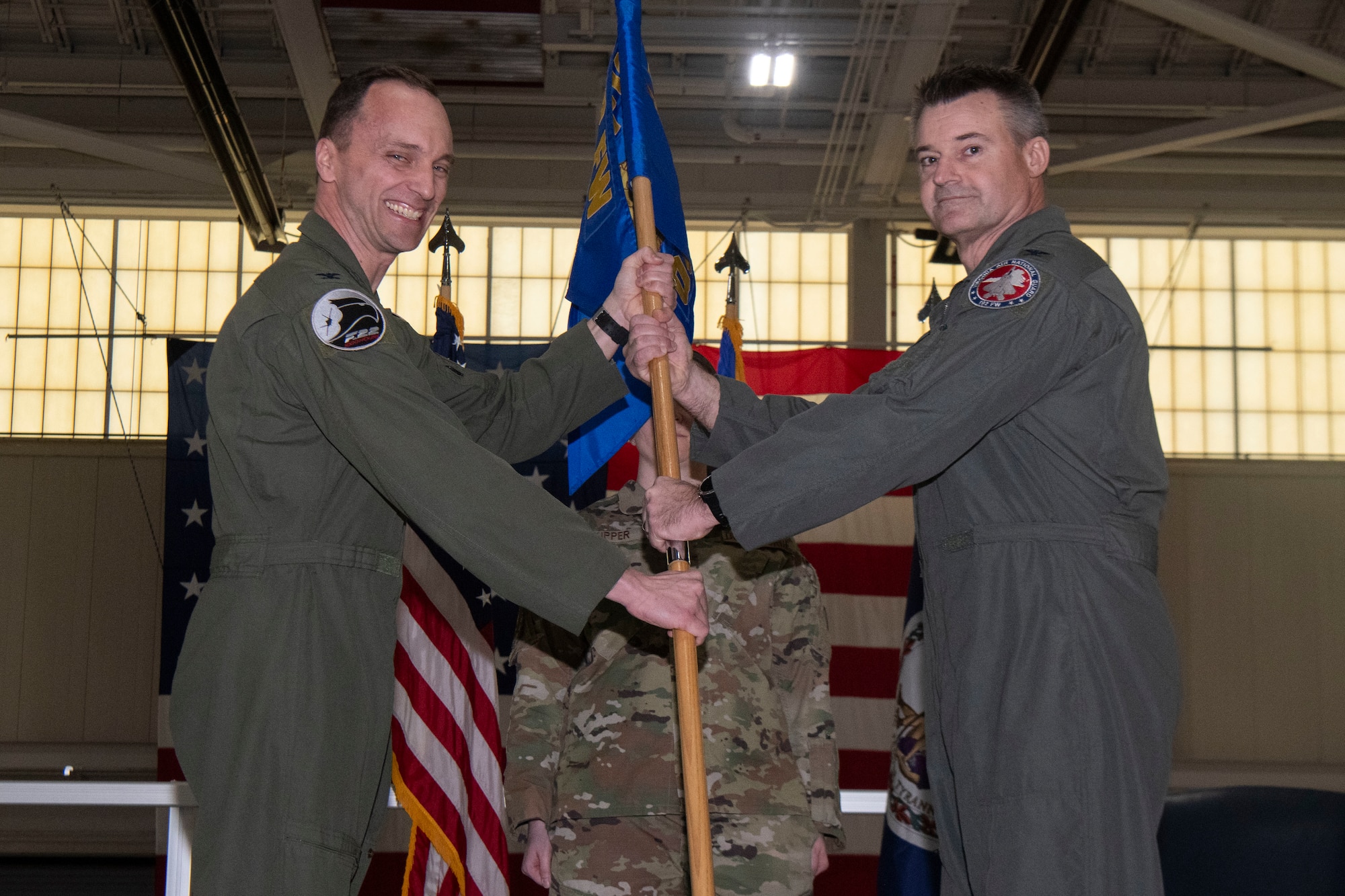 Two Air Force officers holding a guidon, smiling for photo