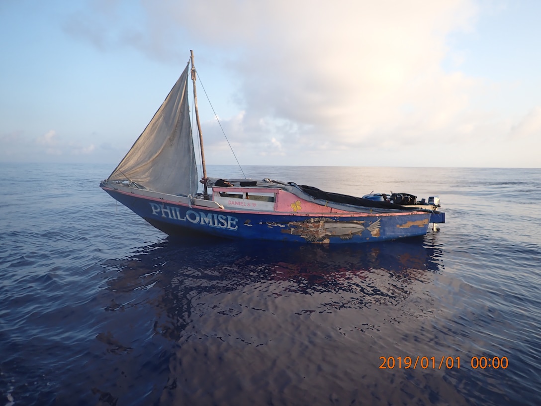 Derelict vessel in water abandoned. On the horizon, a Coast Guard Cutter sails away.