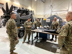 people in military uniforms stand around a table with an aircraft propeller on it