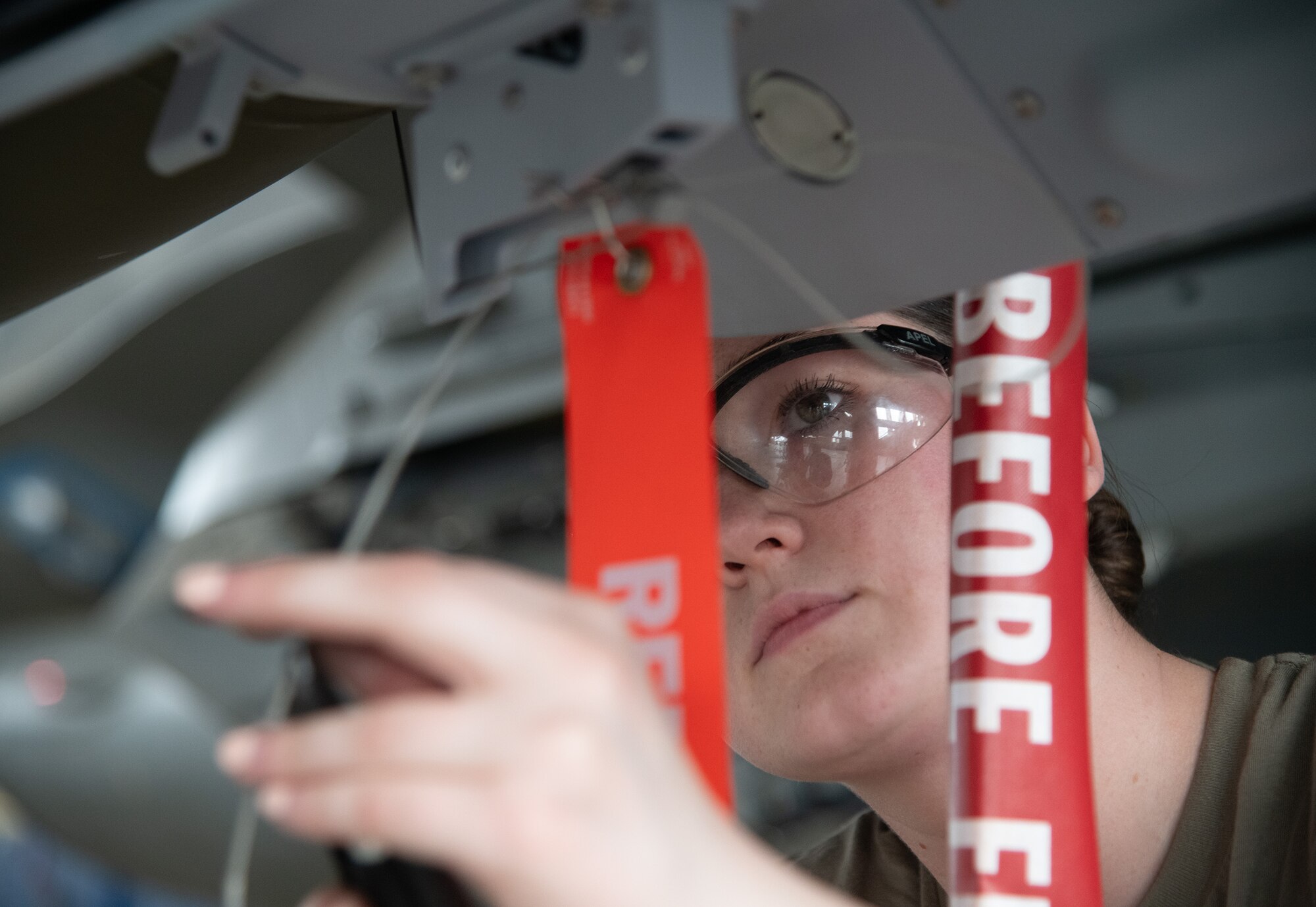 A weapons load crew member, wires the GBU-12 wing release lever on an F-16.
