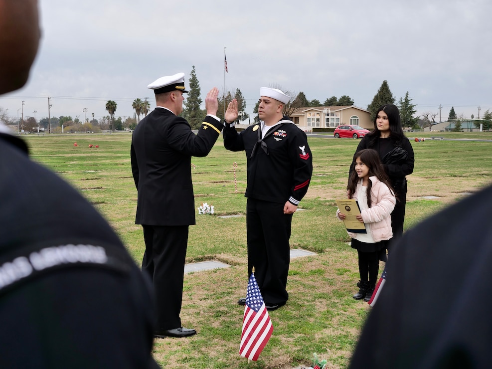 NASL Security Officer ENS Glenn Rakoski administers the oath of re-enlistment to MA2 Eric Mendoza at Floral Memorial Cemetery in Selma, CA. The setting, alongside Mendoza's great-uncles' headstones, buried side-by-side, both Marines and one a Purple Heart recipient, he took the oath, committing to serve another six years in the United States Navy.