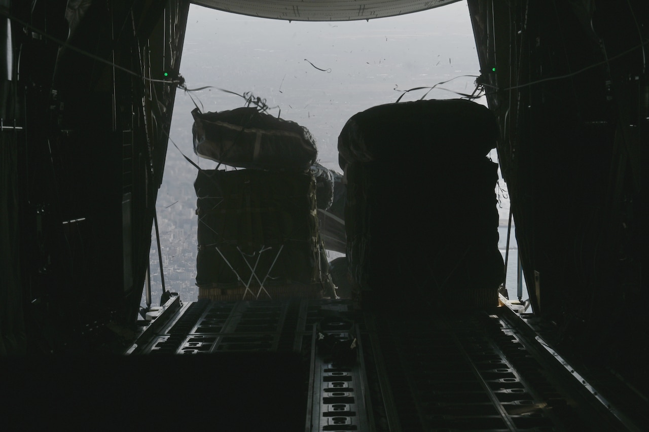 Supplies are dropped from the back of a military aircraft.