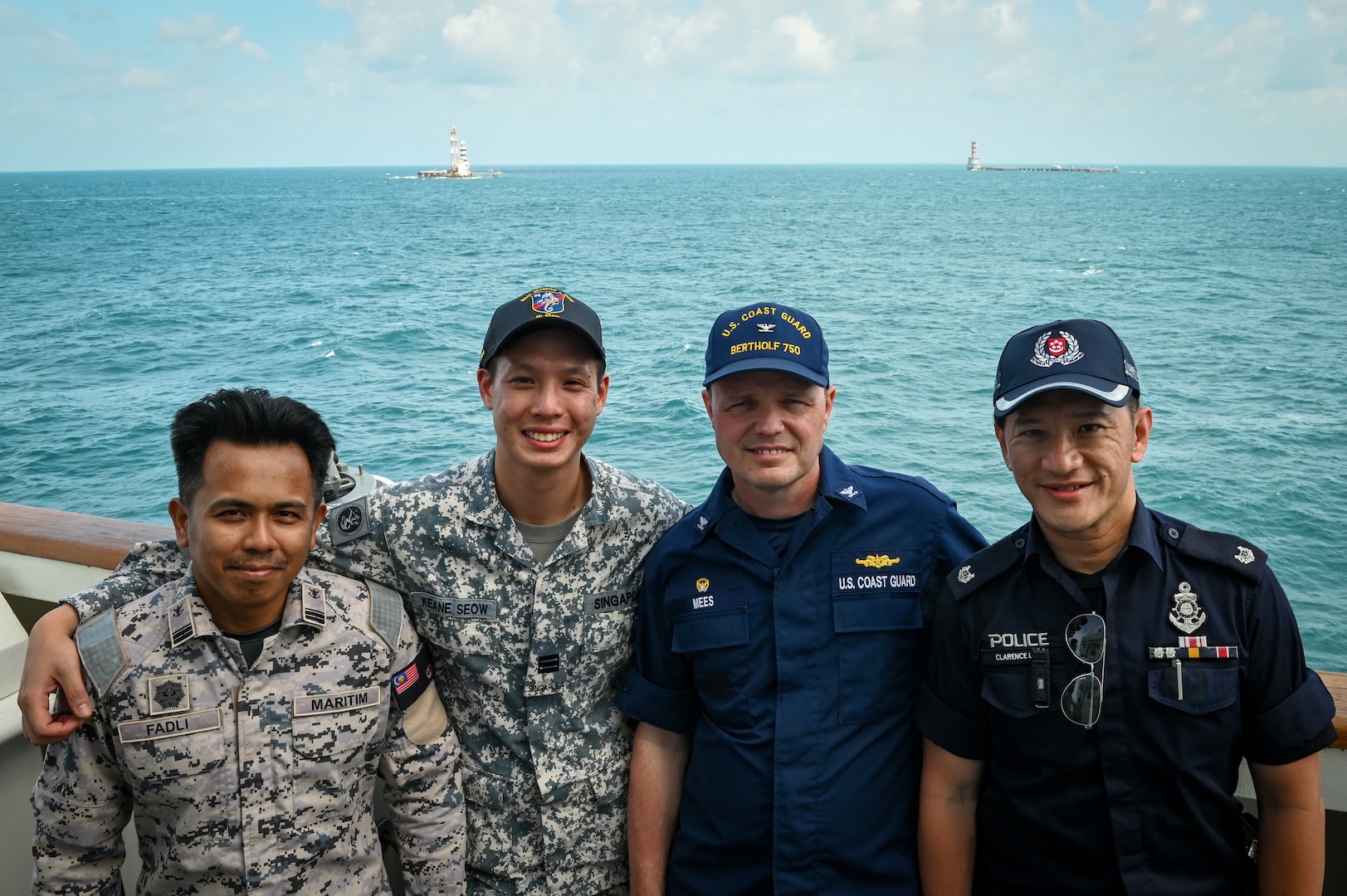 Members from the Malaysian Maritime Enforcement Agency, Republic of Singapore Navy, and Singapore Police Coast Guard stand with Capt. Billy Mees, commanding officer of U.S. Coast Guard Cutter Bertholf (WMSL 750), as the cutter transits next to two lighthouses defining the maritime borders of Malaysia and Singapore, Feb. 28, 2024. The crew of the Bertholf is on a several-month deployment to promote a free and open Indo-Pacific. (U.S. Coast Guard photo by Petty Officer Steve Strohmaier)
