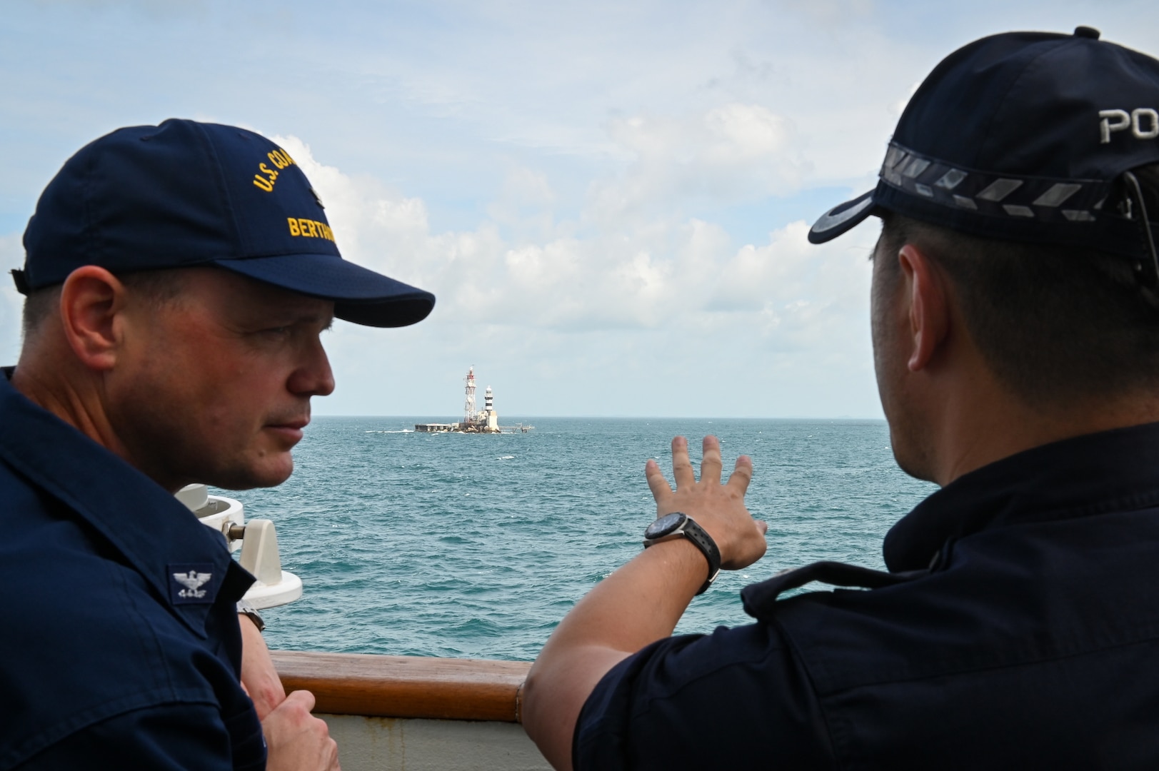 A member of the Singapore Police Coast Guard speaks with Capt. Billy Mees, commanding officer of U.S. Coast Guard Cutter Bertholf (WMSL 750), as the cutter transits next to Horsburgh Lighthouse, a crucial navigation aid near the Singapore Straits, Feb. 28, 2024. The crew of the Bertholf is deployed to the Indo-Pacific region to advance relationships with ally and partner nations. (U.S. Coast Guard photo by Petty Officer Steve Strohmaier)