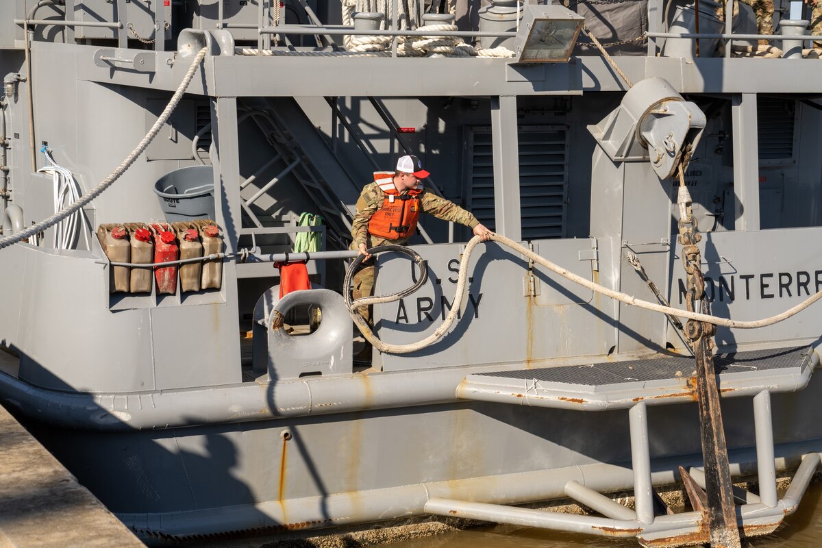 A soldier handles a line aboard a military vessel.