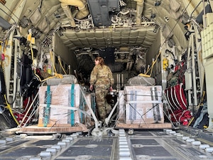 A loadmaster prepares humanitarian aid destined for Gaza on a HC-130J aircraft.