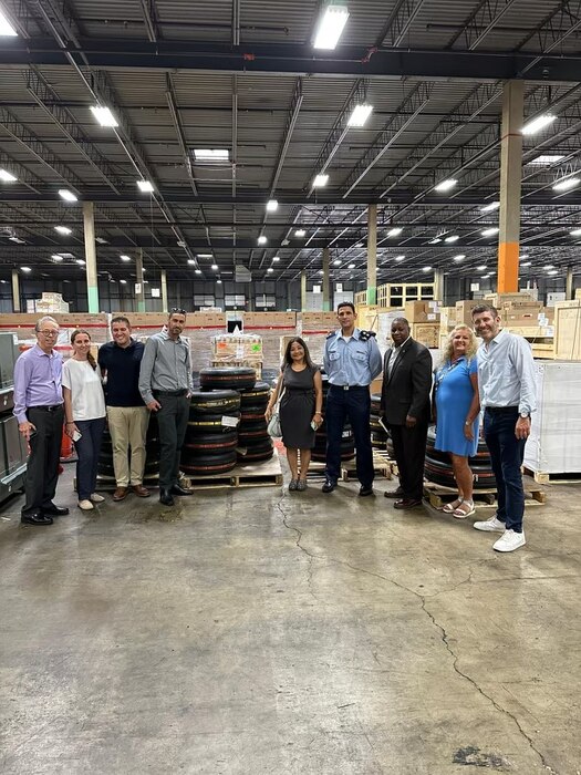 A group of people pose for a photo in a large warehouse.