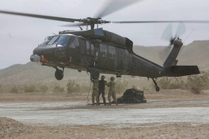 A military helicopter hovers in the air.