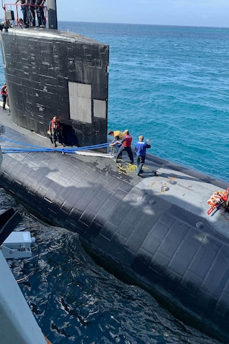 A military ship and submarine sail the ocean.