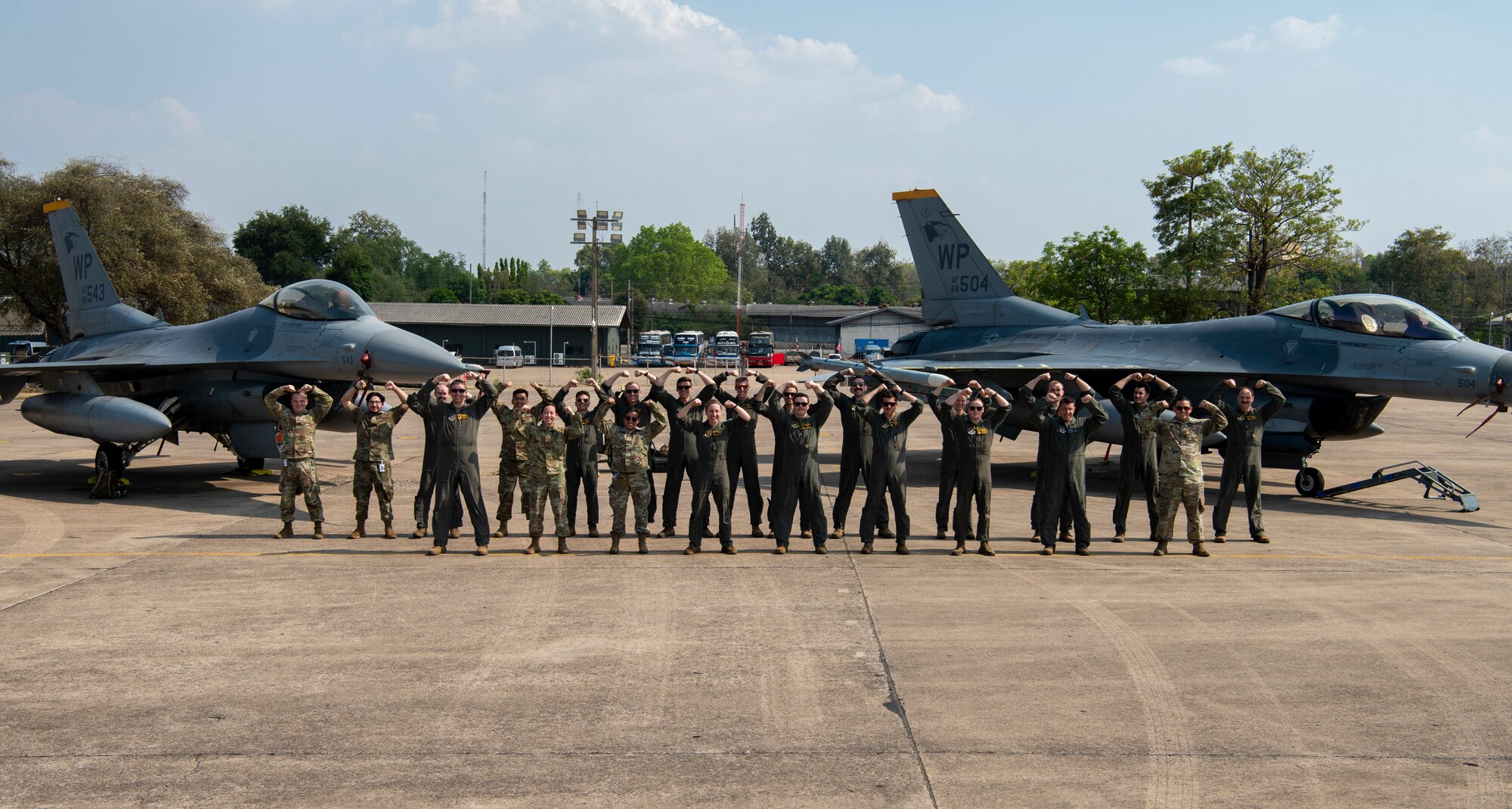 Airmen with the 80th Fighter Squadron strike a ‘Crush ‘Em’ pose for a group photo in front of two F-16 Fighting Falcons