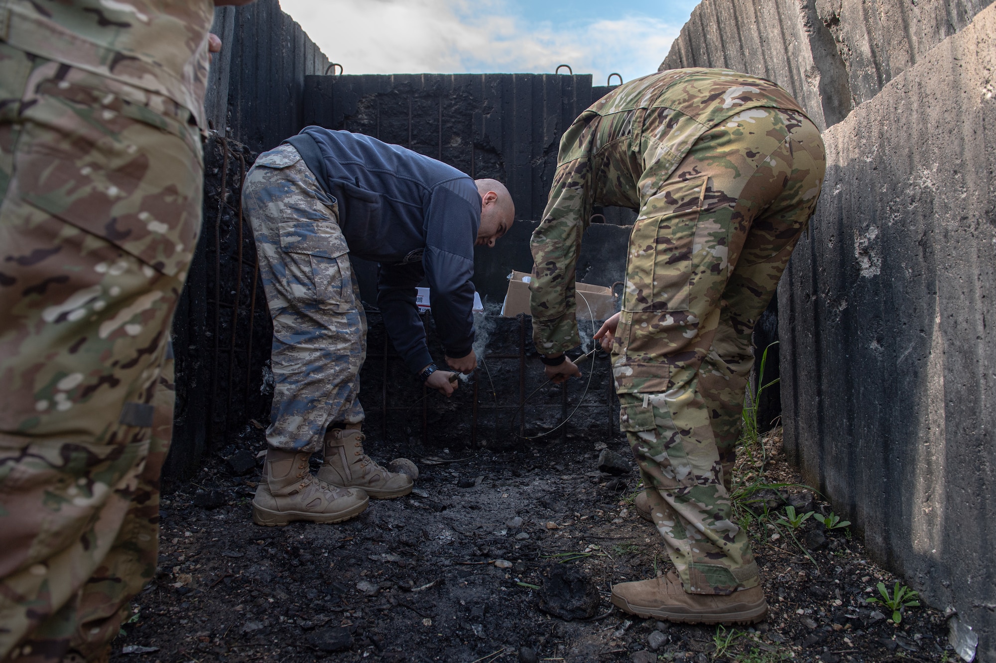 Turkish Air Force 1st Lt. Sinan Cakir assigned to 10th Tanker Base and U.S. Air Force Col. Kevin Lord, 39th Air Base Wing commander, light a fuse to dispose of unserviceable munitions.