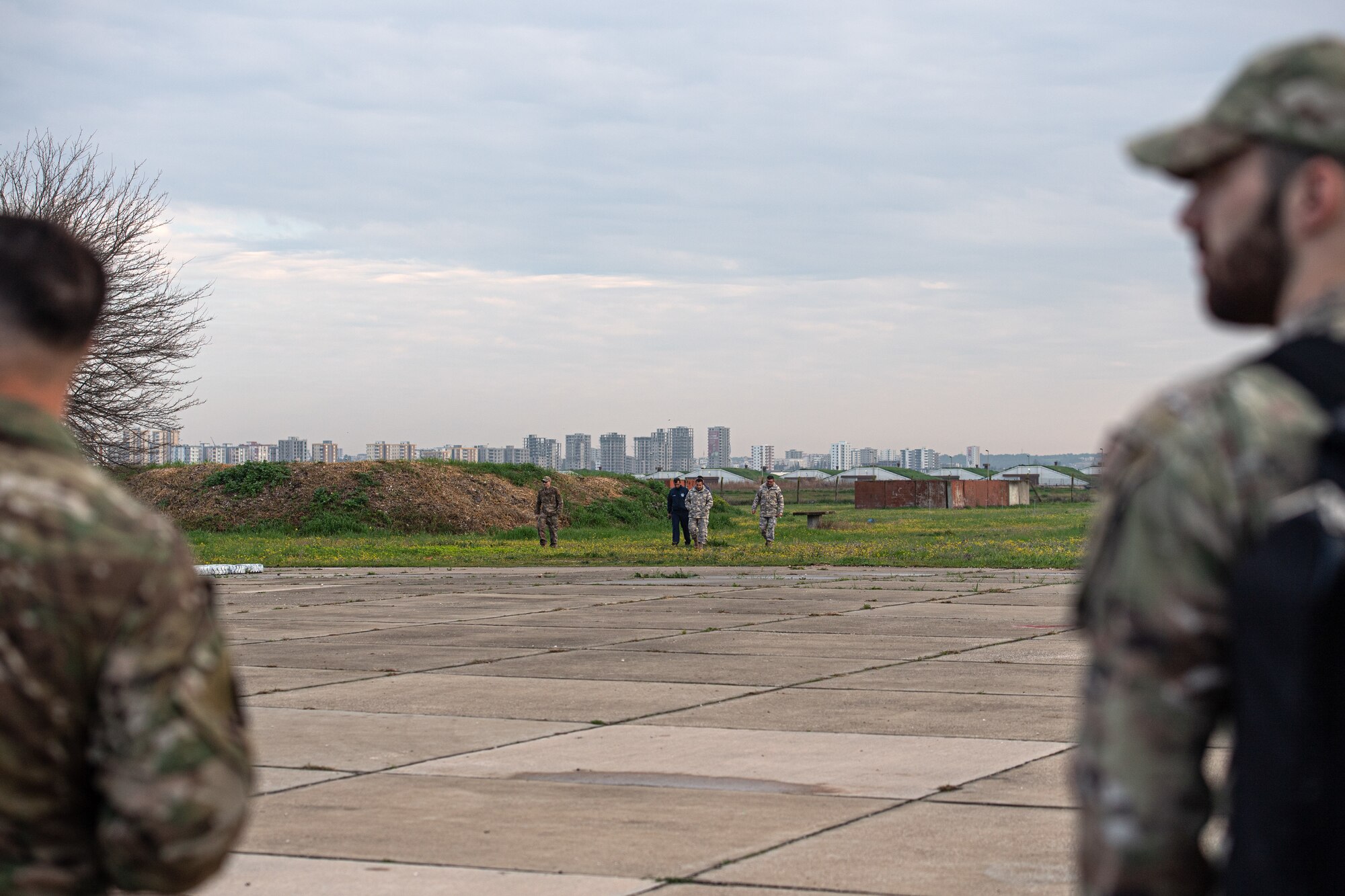 Two Turkish and two U.S. Air Force explosive ordnance disposal teams conduct a site survey at the TurAF disposal site while there are two Airmen in the foreground standing.