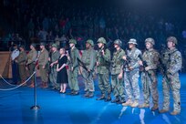 About a dozen Soldiers dressed in various Army uniforms and outfits are standing in a straight line facing the left side of the picture.