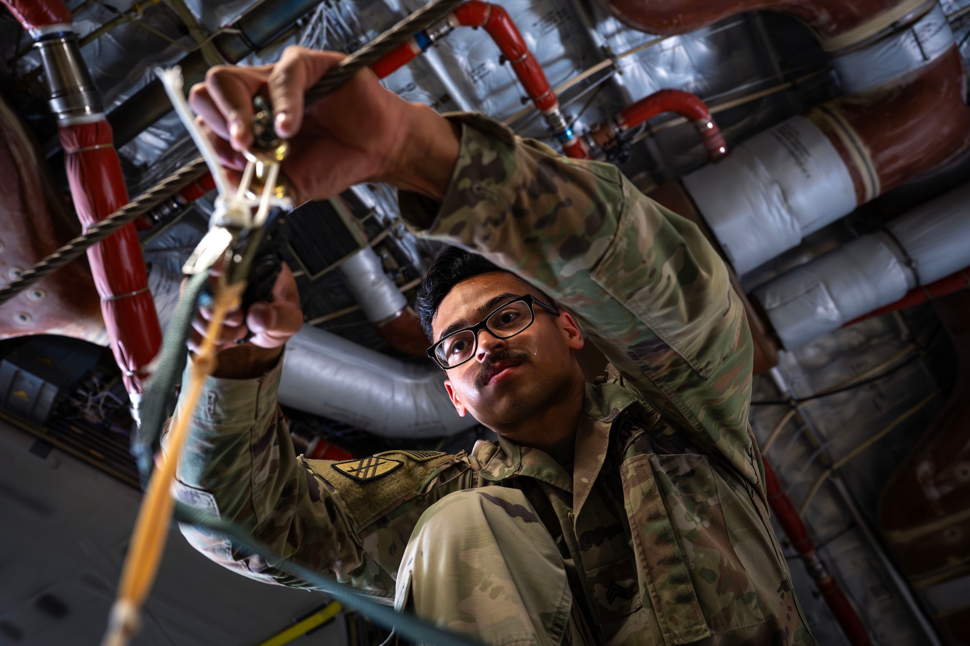 A parachute rigger adjusts a parachute attached to humanitarian aid destined for Gaza inside a C-17.