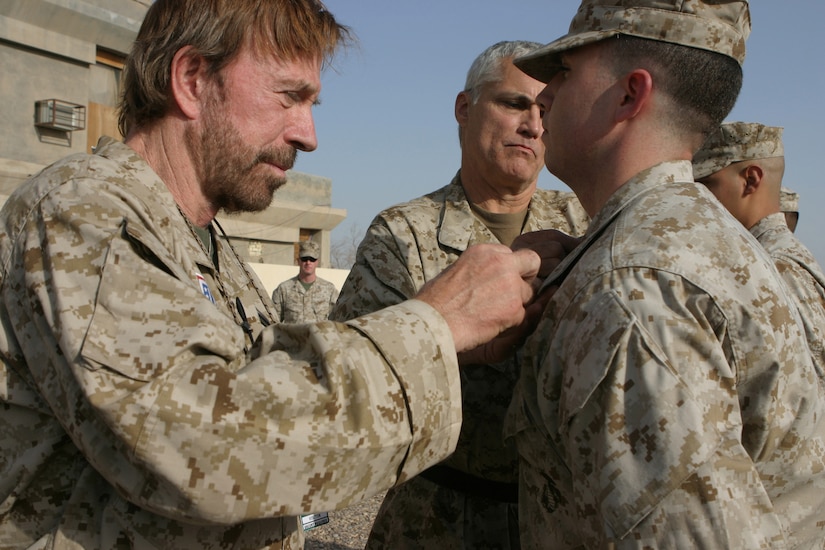 A person pins insignia on a Marine.