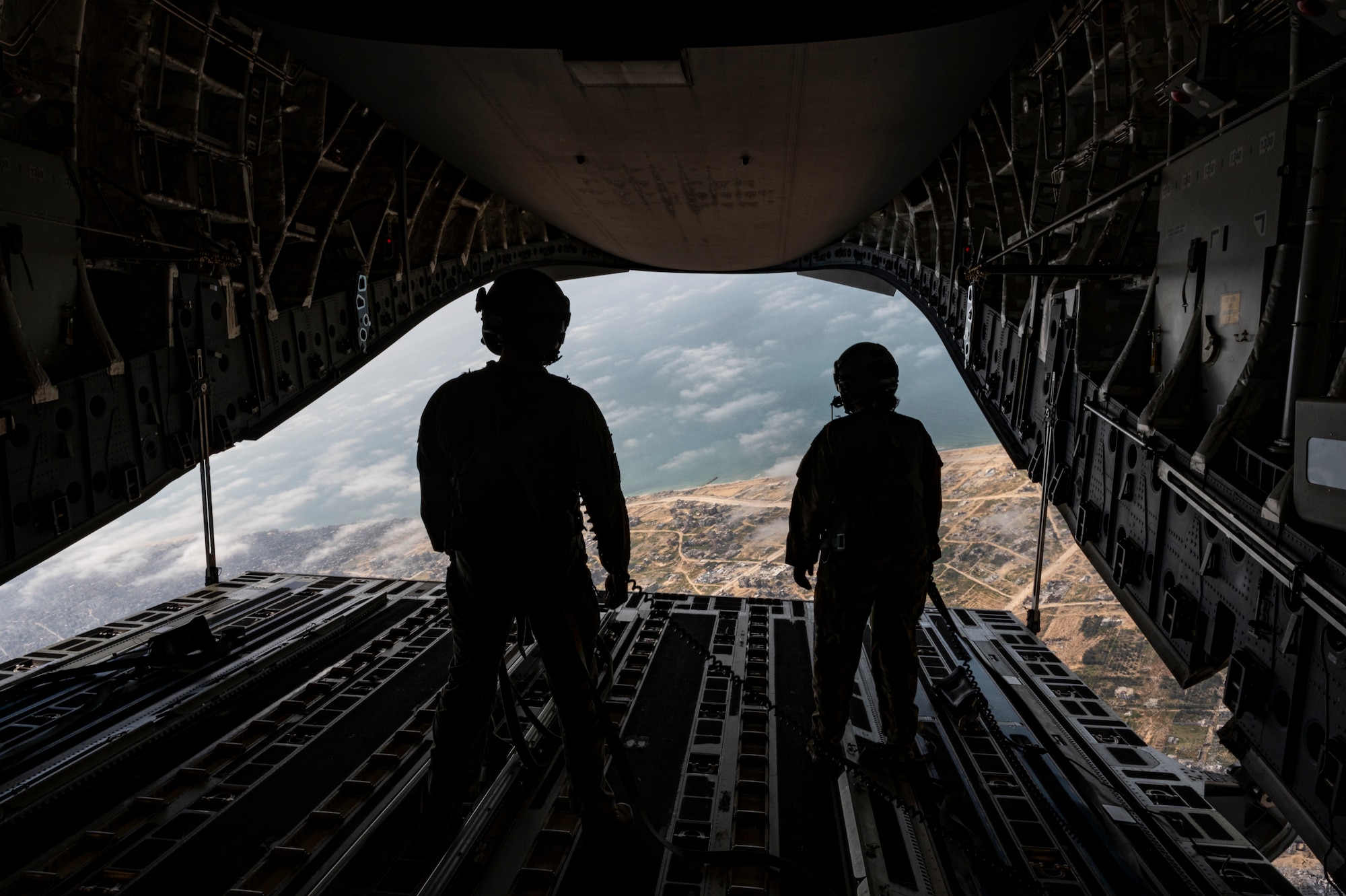 Loadmasters watch as humanitarian aid for Gaza is airdropped from an Air Mobility Command C-17.
