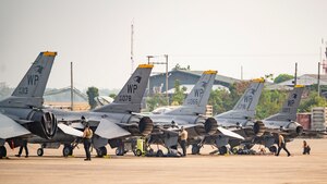Airman 1st Class Darren Ky, left, and Senior Airman Ashley Taylor, both 80th Fighter Generation Squadron aircraft armament systems, perform a gesture of squadron pride while transitting to conduct maintenance on an F-16 Fighting Falcon
