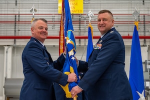 Three men in uniform sit on a stage