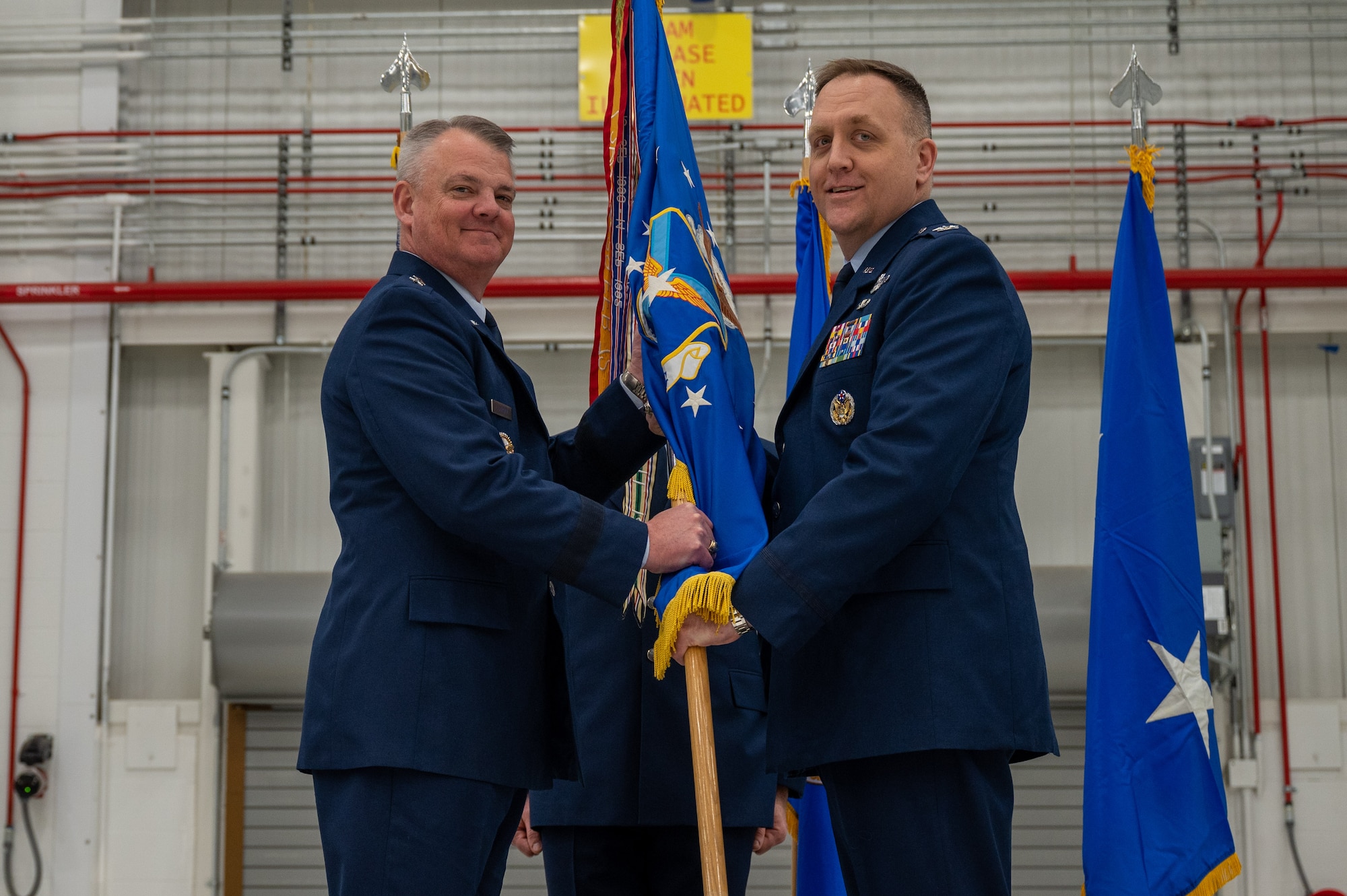 Two men in uniform hold a flag