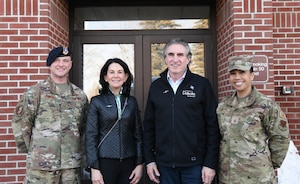 Two military members pose for a photo with two others in front of a building.