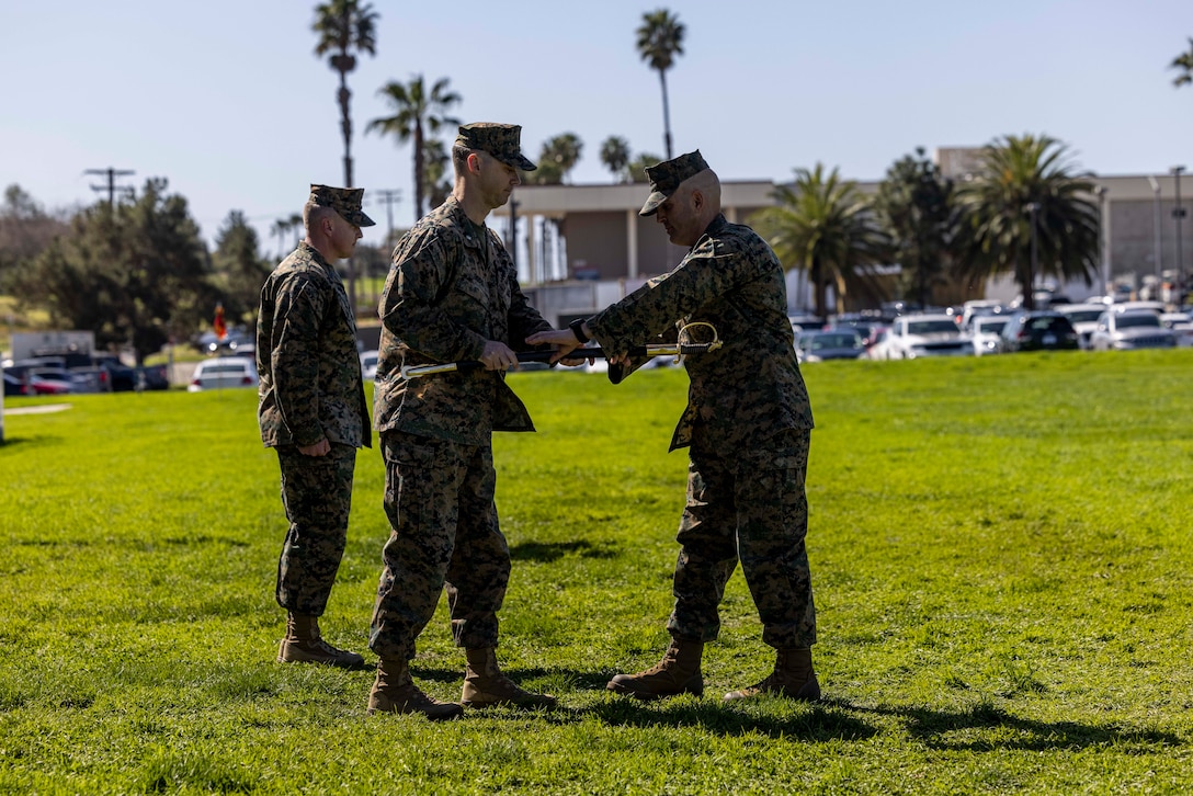 U.S. Marine Corps Lt. Col. Robert Doss, middle, commanding officer of 9th Communication Battalion, I Marine Expeditionary Force Information Group, passes a noncommissioned officer sword to Sgt. Maj. Douglas E. Gardner, incoming sergeant major of 9th Comm. during a relief and appointment ceremony for the battalion on Marine Corps Base Camp Pendleton, California, March 8, 2024. Sgt. Maj. Allen Smith relinquished his post to Gardner and retired after 23 years of service. Gardner is an Illinois native. (U.S. Marine Corps photo by Sgt. Samuel Fletcher)