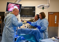 Tech. Sgt. Hilda Mata-Betancourt, 383rd Training Squadron surgical technology course instructor, guides Maj. Gen. Thomas Harrell, 59th Medical Wing commander, and Chief Master Sgt. Kristy Earls, 59th Medical Wing command chief, through an extraction procedure training technical students receive at the 59th Training Group, Joint Base San Antonio-Fort Sam Houston, Texas, March 1, 2024. The training group provides a full spectrum of healthcare education offering a continuum of learning, competency-based training, and credentialing within a tri-service environment. (U.S. Air Force photo by Senior Airman Melody Bordeaux)