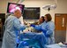 Tech. Sgt. Hilda Mata-Betancourt, 383rd Training Squadron surgical technology course instructor, guides Maj. Gen. Thomas Harrell, 59th Medical Wing commander, and Chief Master Sgt. Kristy Earls, 59th Medical Wing command chief, through an extraction procedure training technical students receive at the 59th Training Group, Joint Base San Antonio-Fort Sam Houston, Texas, March 1, 2024. The training group provides a full spectrum of healthcare education offering a continuum of learning, competency-based training, and credentialing within a tri-service environment. (U.S. Air Force photo by Senior Airman Melody Bordeaux)