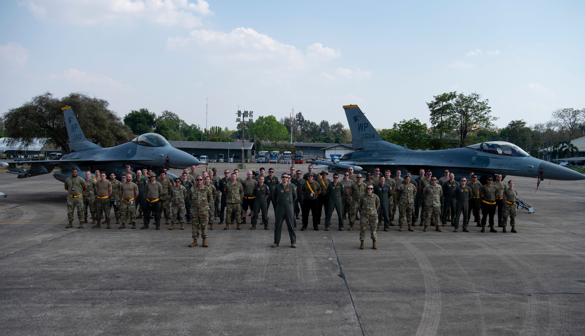 Airmen with the 80th Fighter Squadron and the 80th Fighter Generation Squadron stand at parade rest in front of two F-16 Fighting Falcons
