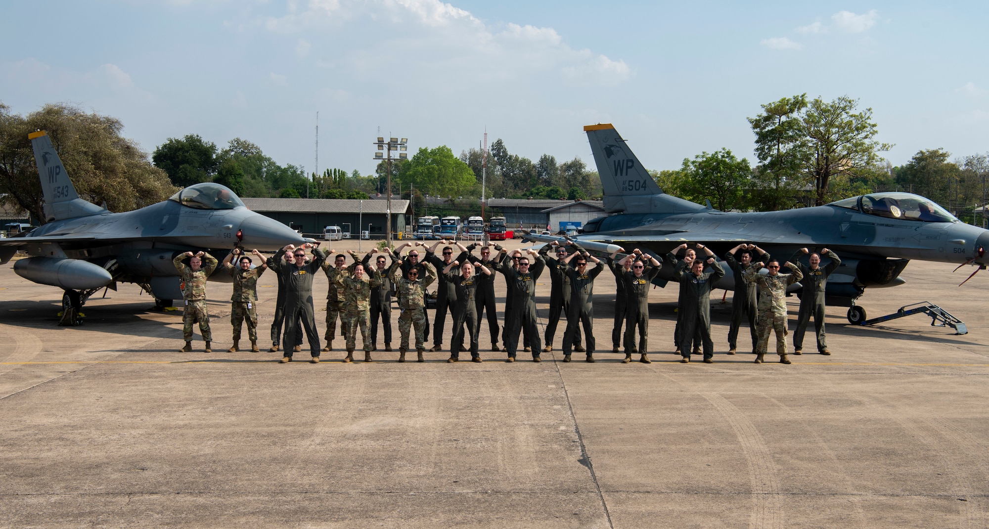 Airmen with the 80th Fighter Squadron strike a ‘Crush ‘Em’ pose for a group photo in front of two F-16 Fighting Falcons
