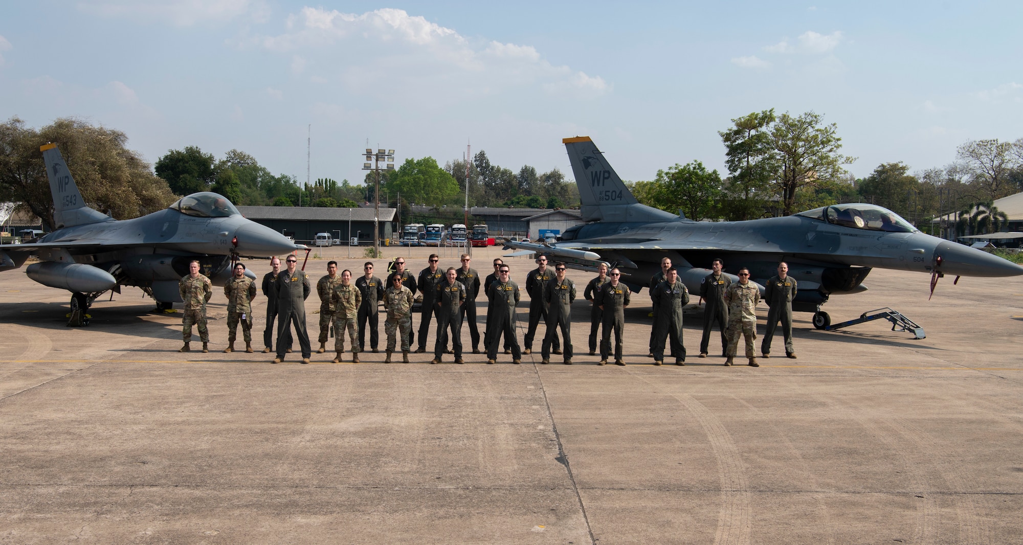 Airmen with the 80th Fighter Squadron stand at parade rest in front of two F-16 Fighting Falcons