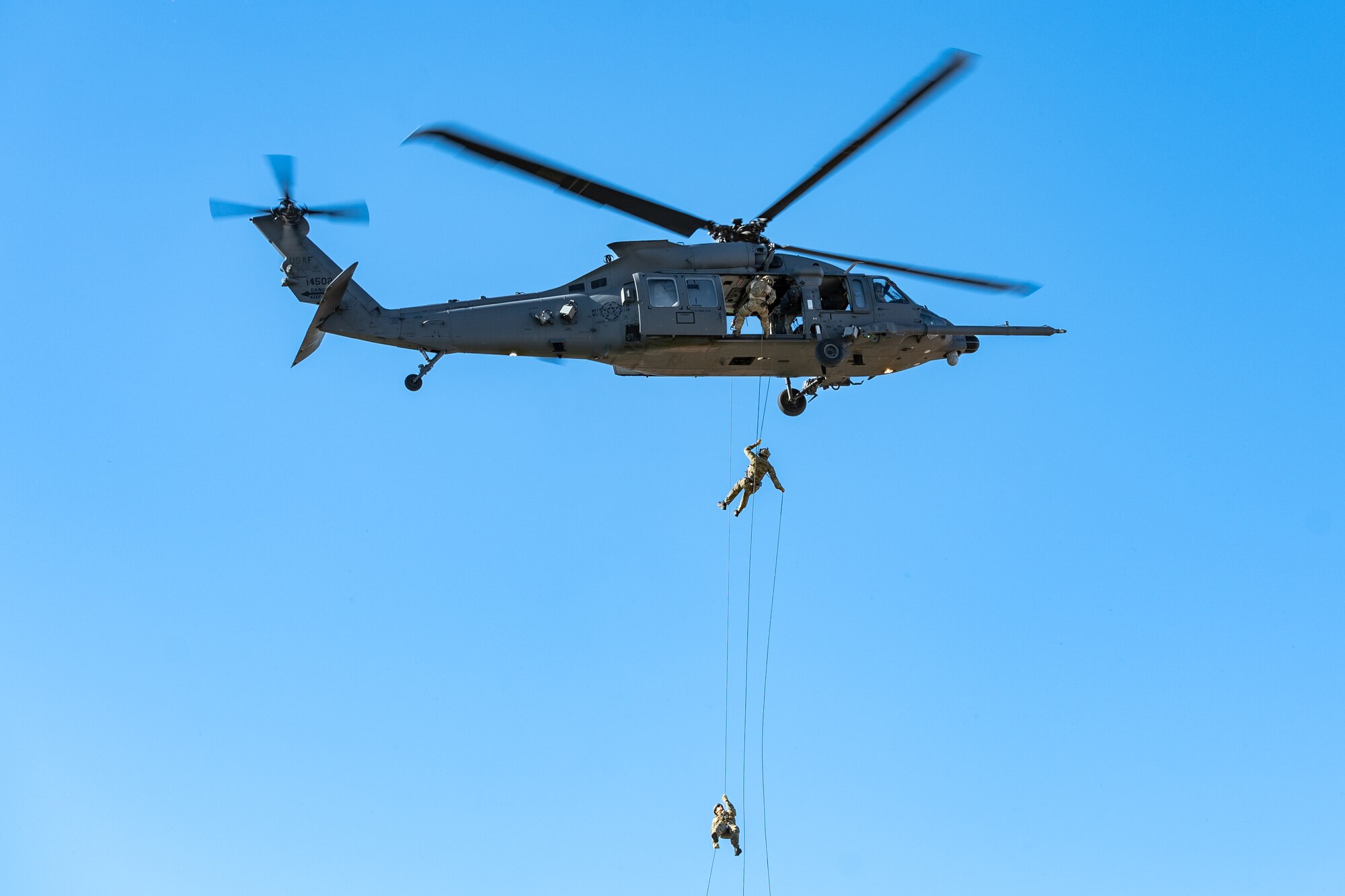 The Air Force Special Warfare Exhibition team performs a fast rope infiltration demonstration off a HH-60W Jolly Green II in honor of the 2024 Air Force and Marine Corps Trials competition at Nellis Air Force Base, Nevada, March 8, 2024.