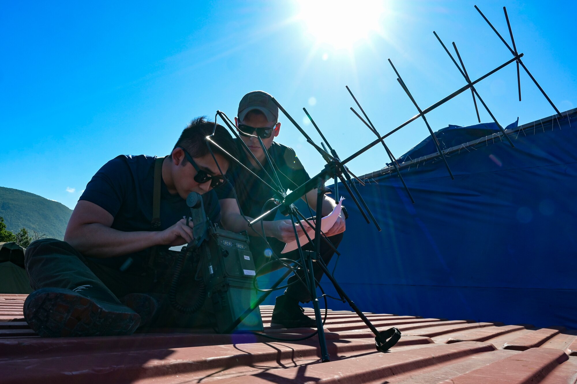 U.S. Air Force Senior Airman Justin Moon, a 1st Special Operations Communications Squadron special missions technician, left, and Senior Airman Daniel Chavez, a 1st Special Operations Wing planner, right, set up communications equipment during exercise Tropical Dagger at Kingston, Jamaica, Feb. 21, 2024.