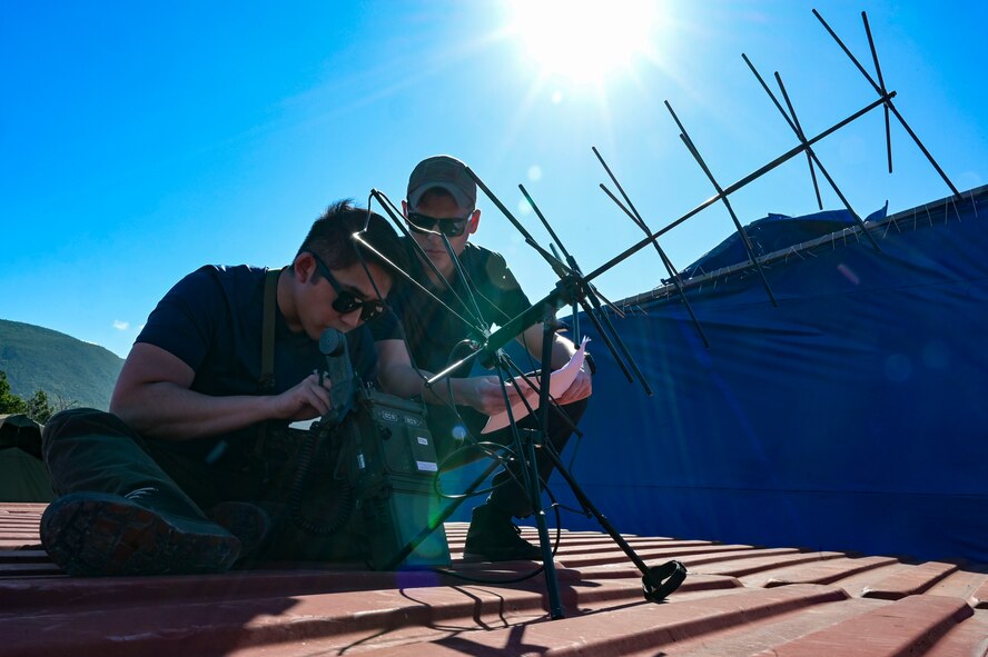 U.S. Air Force Senior Airman Justin Moon, a 1st Special Operations Communications Squadron special missions technician, left, and Senior Airman Daniel Chavez, a 1st Special Operations Wing planner, right, set up communications equipment during exercise Tropical Dagger at Kingston, Jamaica, Feb. 21, 2024.