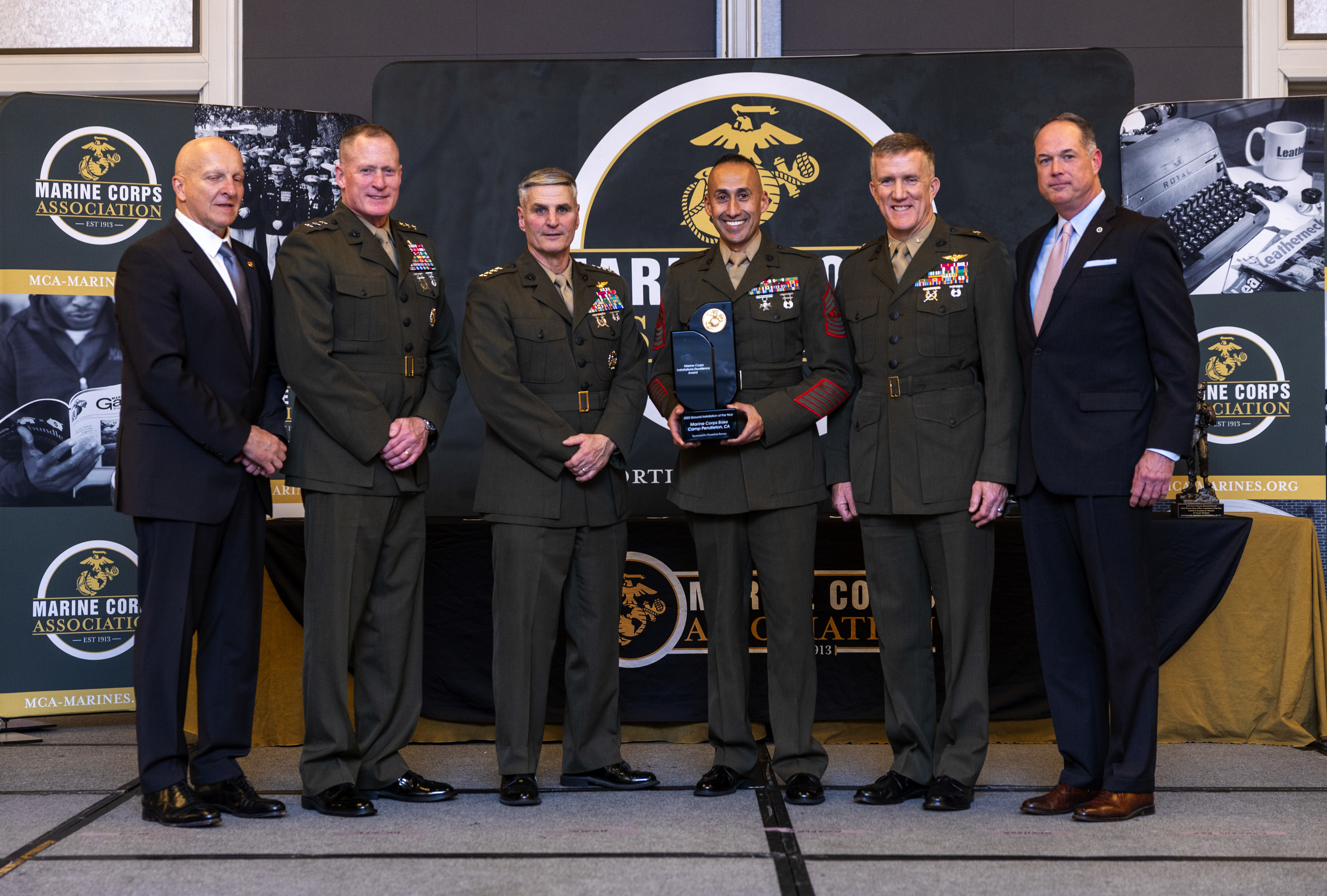 U.S. Marine Corps Gen. Christopher J. Mahoney, the Assistant Commandant of the Marine Corps, and Lt. Gen. Edward Banta , the Deputy Commandant for Installations & Logistics, presents an award to Sgt. Maj. Fausto Cabrera, sergeant major for Marine Corps Installations West- Marine Corps Base Camp Pendleton, and Brig. Gen. Jason G. Woodworth, commanding general for Marine Corps Installations West- Marine Corps Base Camp Pendleton, at the Hilton Alexandria Mark Center, Alexandria, VA on March 6, 2024. Marine Corps Base Camp Pendleton, CA received the Marine Corps Installation Excellence Award the Ground Installation of the Year award. (U.S. Marine Corps photo by Lance Cpl. Juaquin Greaves)