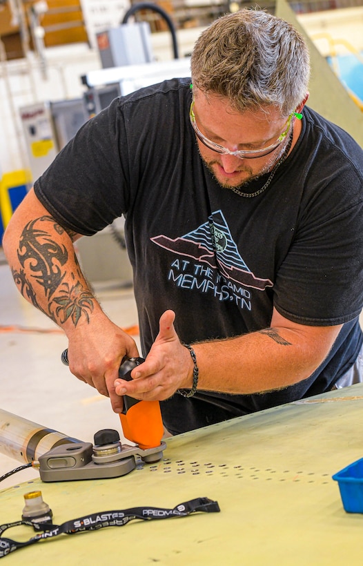 230726-N-DG679-1016
JACKSONVILLE, Fla. (July 26, 2023) 
Sheet Metal Mechanic Brett McDonald assigned to the Fleet Readiness Center Southeast (FRCSE) F-5 Aircraft Production Line, uses an E-Drill to remove metal fasteners on an F-5 Tiger II vertical stabilizer. FRCSE’s F-5 Production Line is the first to implement the E-Drill within the NAVAIR enterprise. The device will significantly reduce the time it takes to remove the thousands of rivets typically replaced during in-depth depot-level maintenance. (U.S. Navy Photo by Toiete Jackson