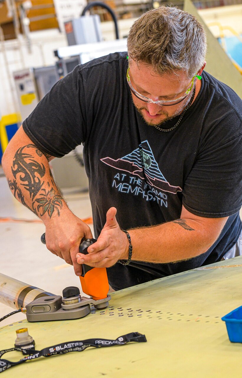 230726-N-DG679-1016
JACKSONVILLE, Fla. (July 26, 2023) 
Sheet Metal Mechanic Brett McDonald assigned to the Fleet Readiness Center Southeast (FRCSE) F-5 Aircraft Production Line, uses an E-Drill to remove metal fasteners on an F-5 Tiger II vertical stabilizer. FRCSE’s F-5 Production Line is the first to implement the E-Drill within the NAVAIR enterprise. The device will significantly reduce the time it takes to remove the thousands of rivets typically replaced during in-depth depot-level maintenance. (U.S. Navy Photo by Toiete Jackson