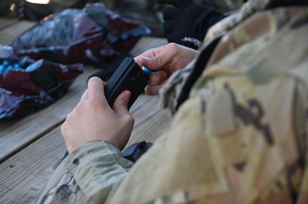 Cadet from Angelo State University Air Force ROTC loads a training magazine in preparation for an annual field exercise at Goodfellow Air Force Base, Texas, March 1, 2024. Cadets operated in a simulated environment where they learned tactics on how to spot an Improvised Explosive Device and how to facilitate entry control points. (U.S. Air Force photo by Airman James Salellas)