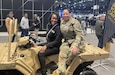 Female Civilian and Female Soldier sit on an Army All-Terrain vehicle on display at the Chicago Auto Show