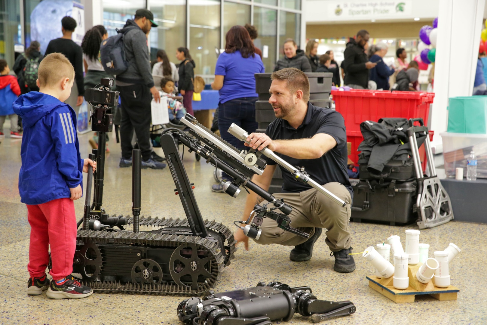 A robotics technician in NSWC IHD’s Unmanned Systems Branch, and a young attendee of the History, Industry, Technology and Science Expo interact with an explosive ordnance disposal robot at St. Charles High School in Waldorf, Maryland, on March 9.