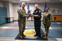 U.S. Air Force Maj. Gen. Daniel A. DeVoe, left, Air Force District of Washington and 320th Air Expeditionary Wing commander, joined by U.S. Air Force Chief Master Sgt. Charmaine Kelley, right, AFDW and 320th AEW command chief, presents an award to police Sgt. 1st Class Robert Cox, middle, 11th Security Forces Squadron Alpha flight chief, on Joint Base Anacostia-Bolling, Washington, D.C., March 12, 2024. Cox was awarded the Outstanding Security Forces Flight-Level Civilian award for duties performed while serving as a flight chief for the squadron.