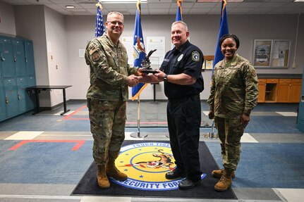 U.S. Air Force Maj. Gen. Daniel A. DeVoe, left, Air Force District of Washington and 320th Air Expeditionary Wing commander, joined by U.S. Air Force Chief Master Sgt. Charmaine Kelley, right, AFDW and 320th AEW command chief, presents an award to police Sgt. 1st Class Robert Cox, middle, 11th Security Forces Squadron Alpha flight chief, on Joint Base Anacostia-Bolling, Washington, D.C., March 12, 2024. Cox was awarded the Outstanding Security Forces Flight-Level Civilian award for duties performed while serving as a flight chief for the squadron.