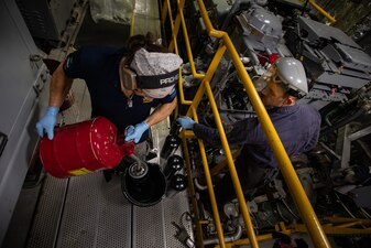EN2 Erick D. Vuckson, right, and civil service mariner Liam A. DeFronzo prime fuel filters for the engines aboard USS Mobile (LCS 26) in the South China Sea.