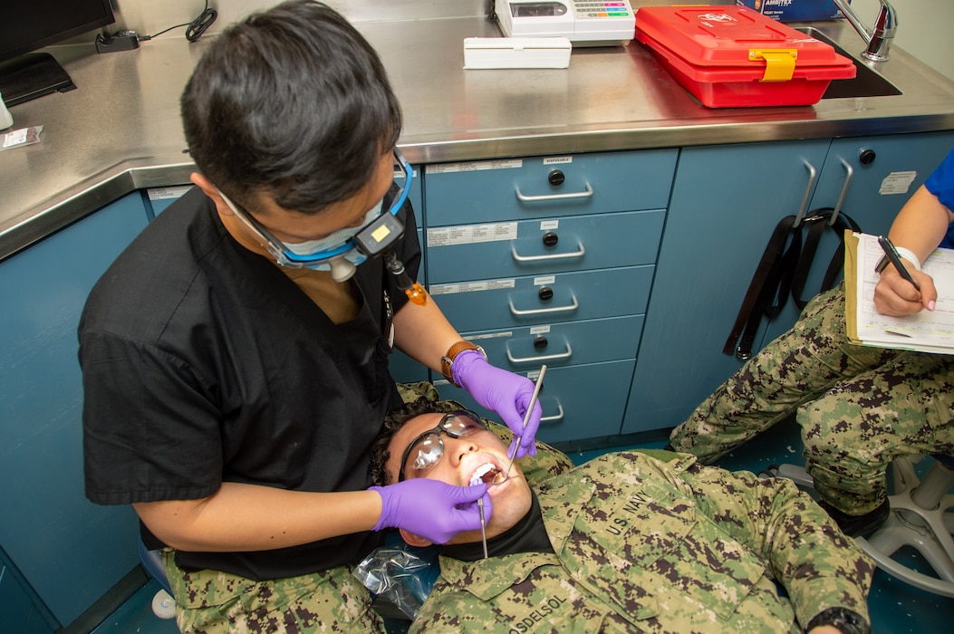 240306-N-UF592-1009 YOKOSUKA, Japan (March 6, 2024) Lt. Patrick Gomez, left, from Las Vegas, conducts a dental examination on Aviation Ordnanceman Airman Edward Rayos Del Sol, from Long Beach, California, in the dental office aboard the U.S. Navy’s only forward-deployed aircraft carrier, USS Ronald Reagan (CVN 76), while in-port Commander, Fleet Activities Yokosuka, March 6.  Ronald Reagan, the flagship of Carrier Strike Group 5, provides a combat-ready force that protects and defends the United States, and supports alliances, partnerships and collective maritime interests in the Indo-Pacific region. (U.S. Navy photo by Mass Communication Specialist 3rd Class Eric Stanton)